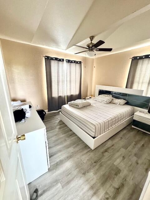 bedroom with hardwood / wood-style floors, ceiling fan, and vaulted ceiling