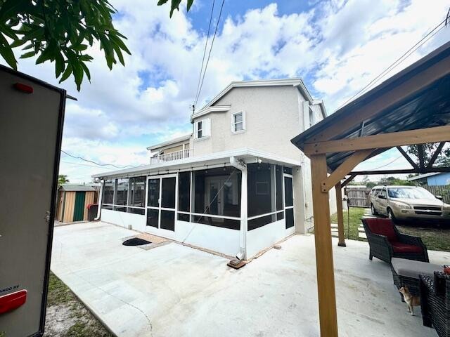 back of property with a sunroom and a patio area