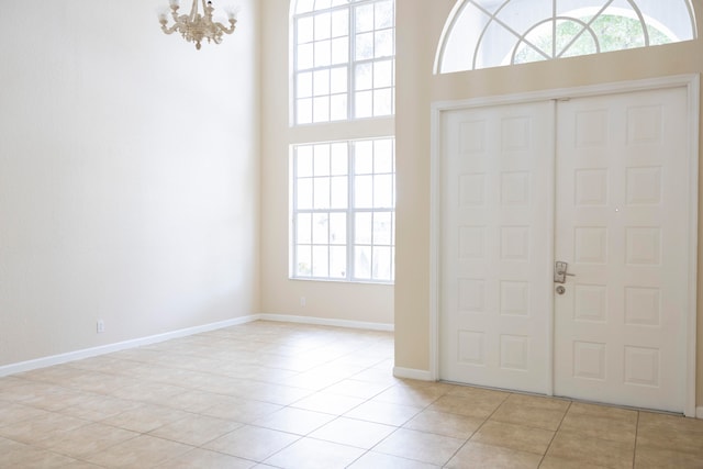 entrance foyer featuring light tile patterned floors, a high ceiling, and a notable chandelier