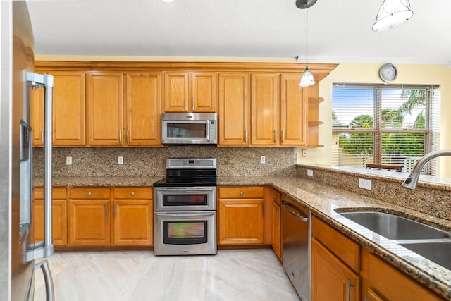 kitchen with stainless steel appliances, backsplash, decorative light fixtures, sink, and dark stone countertops