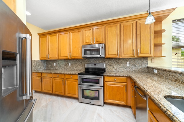 kitchen with light stone counters, appliances with stainless steel finishes, a textured ceiling, backsplash, and pendant lighting