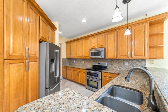 kitchen with sink, appliances with stainless steel finishes, hanging light fixtures, light wood-type flooring, and decorative backsplash