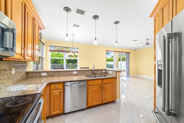 kitchen with light stone counters, hanging light fixtures, ceiling fan, backsplash, and appliances with stainless steel finishes