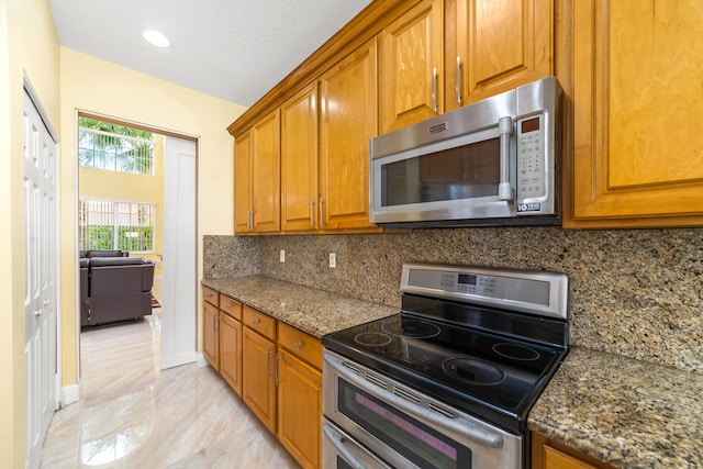 kitchen with stainless steel appliances, dark stone countertops, a textured ceiling, and decorative backsplash