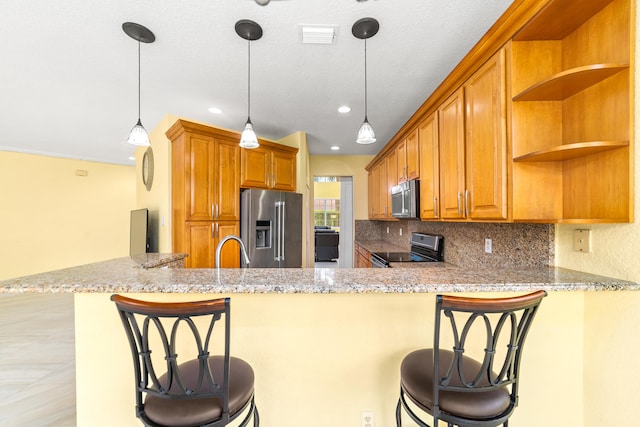 kitchen featuring kitchen peninsula, a kitchen bar, and appliances with stainless steel finishes