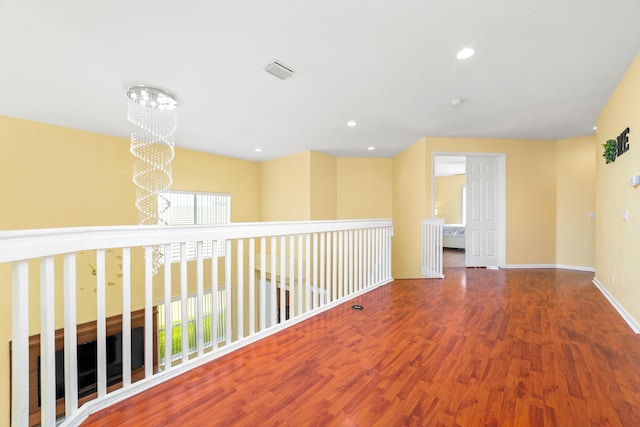 empty room featuring wood-type flooring, a notable chandelier, and a healthy amount of sunlight