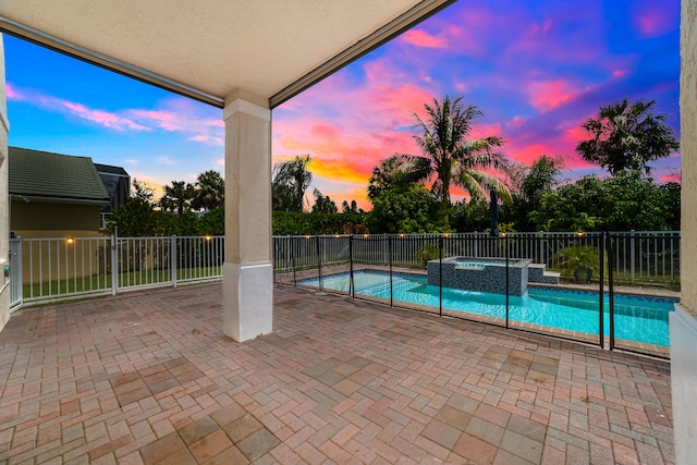 pool at dusk with a patio and an in ground hot tub