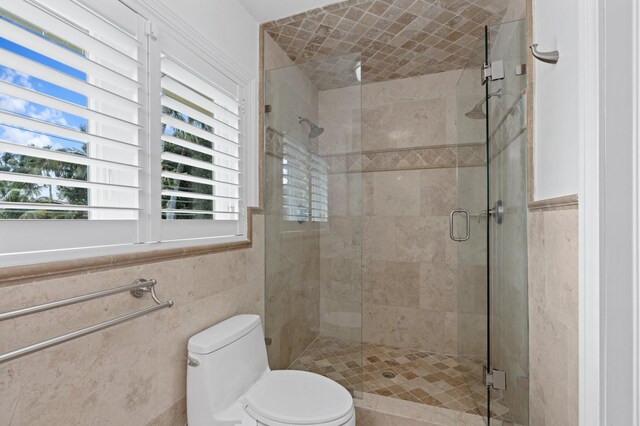 bathroom featuring a shower with shower door, tile walls, and toilet