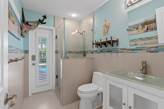 bathroom with vanity, a shower with door, tile walls, tile patterned flooring, and toilet