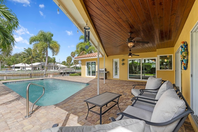 view of swimming pool featuring a water view, ceiling fan, and a patio area