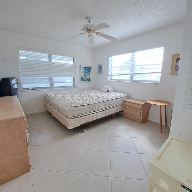 bedroom with ceiling fan, a textured ceiling, and light tile patterned floors