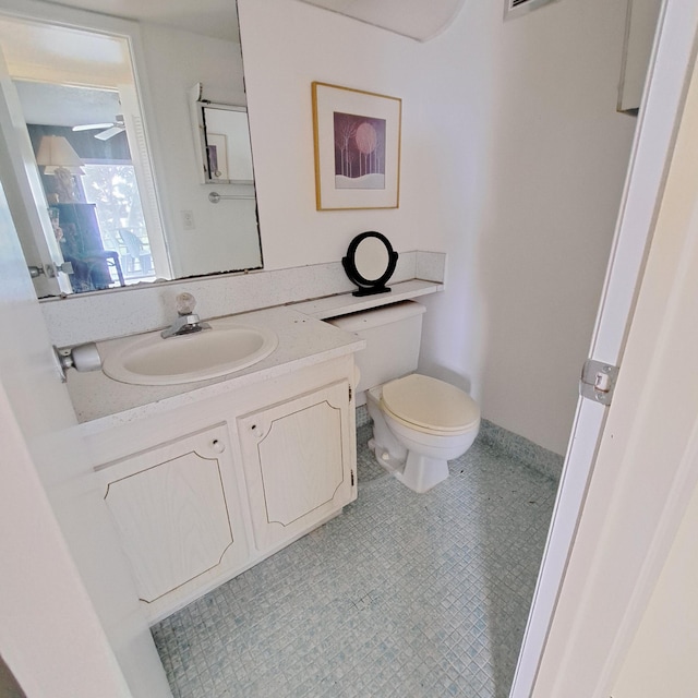 bathroom with toilet, vanity, tile patterned floors, and ceiling fan