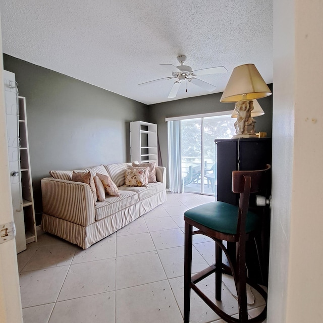 living room with ceiling fan, a textured ceiling, and light tile patterned floors