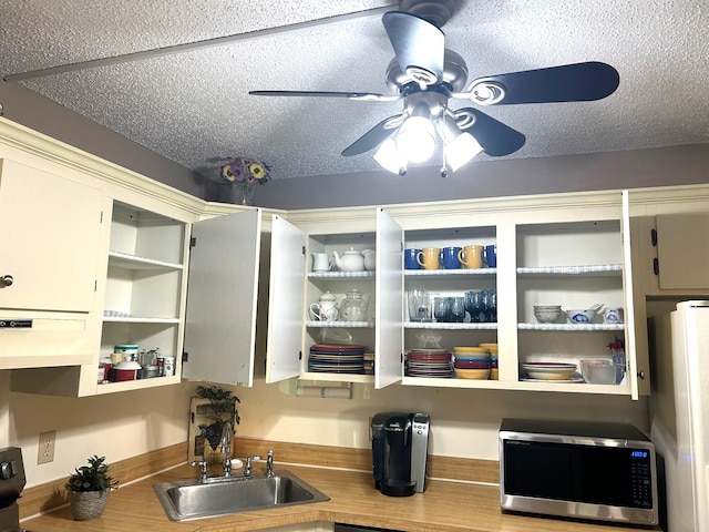 kitchen featuring a textured ceiling, ceiling fan, sink, and white refrigerator