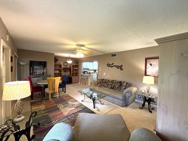 living room featuring a textured ceiling, carpet flooring, and ceiling fan