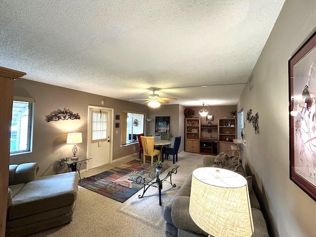 living room with ceiling fan, a textured ceiling, and carpet floors