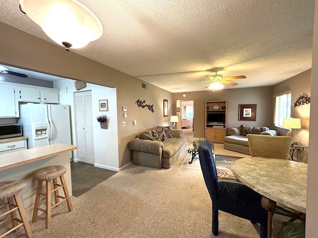 dining space with a textured ceiling, a healthy amount of sunlight, and dark carpet