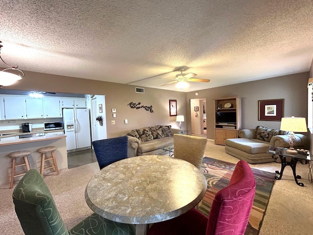 carpeted dining room with a textured ceiling and ceiling fan