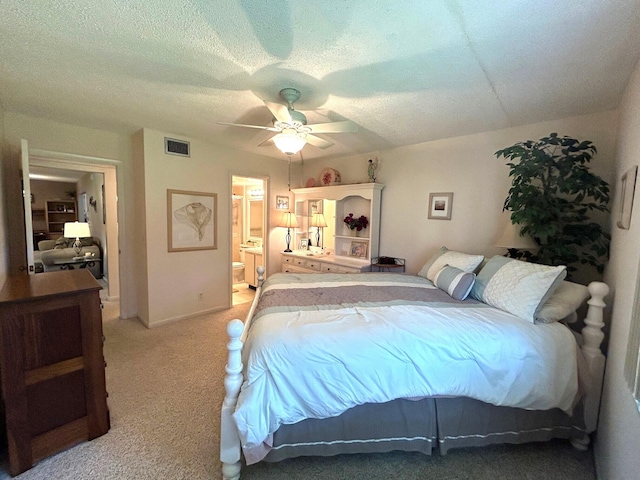 carpeted bedroom featuring a textured ceiling, ceiling fan, and ensuite bath