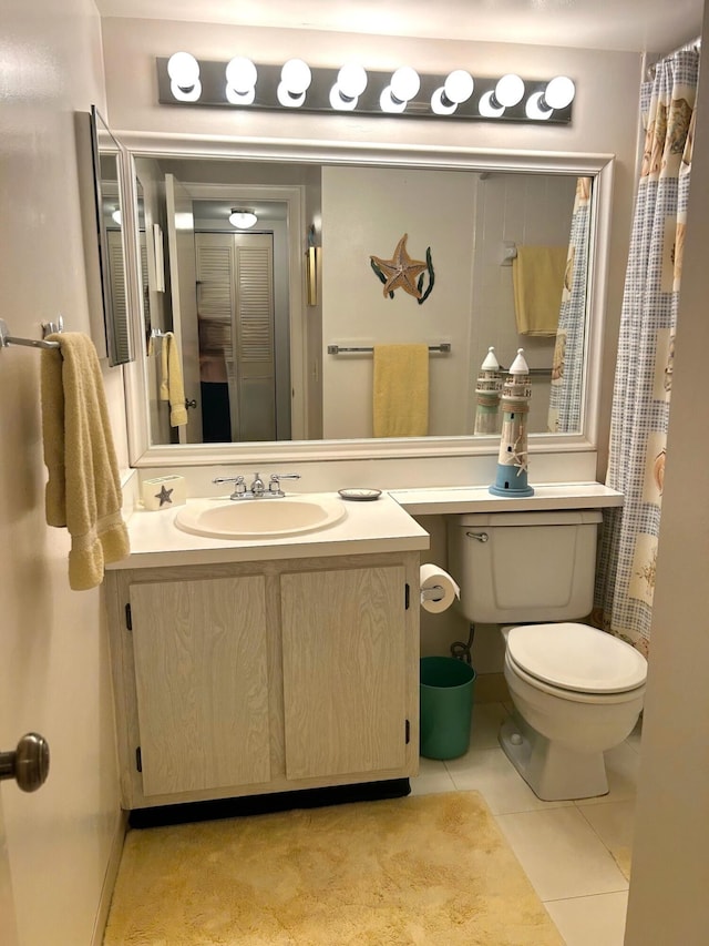 bathroom with toilet, vanity, and tile patterned floors