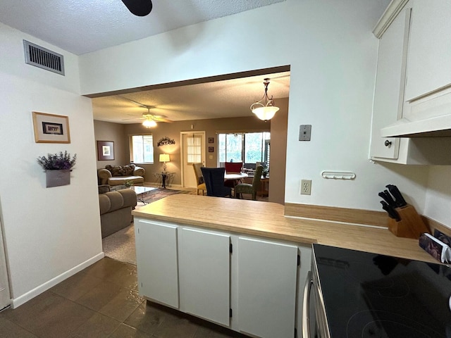 kitchen with hanging light fixtures, ceiling fan, stove, and white cabinets