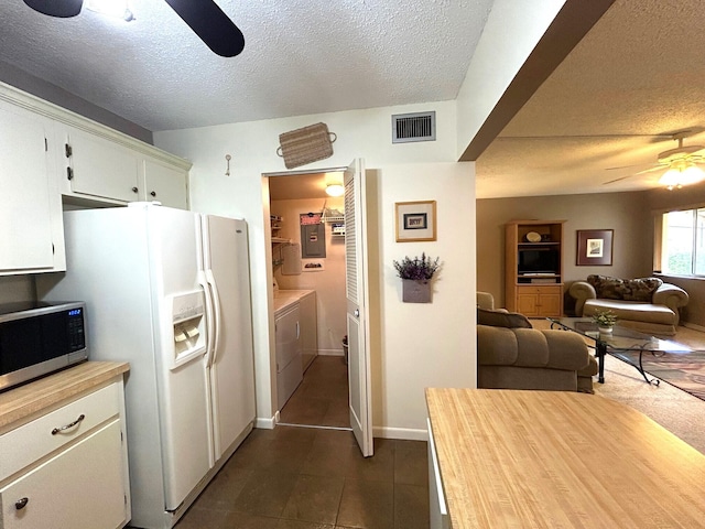 kitchen featuring white cabinetry, ceiling fan, a textured ceiling, white refrigerator with ice dispenser, and washing machine and clothes dryer