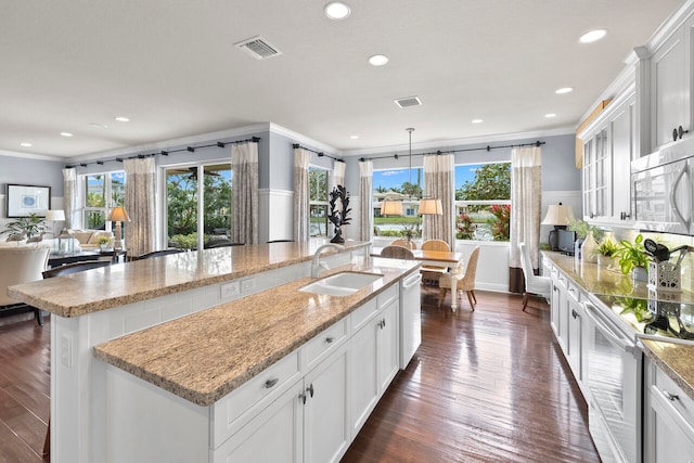 kitchen with stainless steel appliances, white cabinetry, sink, dark hardwood / wood-style floors, and a spacious island