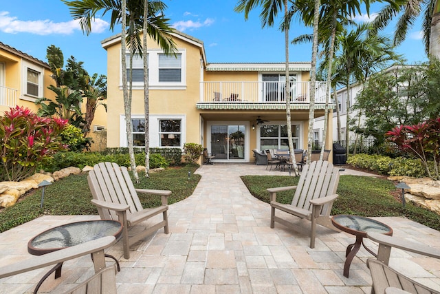 rear view of property featuring ceiling fan, a balcony, and a patio area