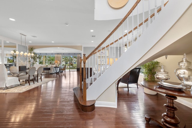 staircase with hardwood / wood-style floors, a chandelier, and crown molding