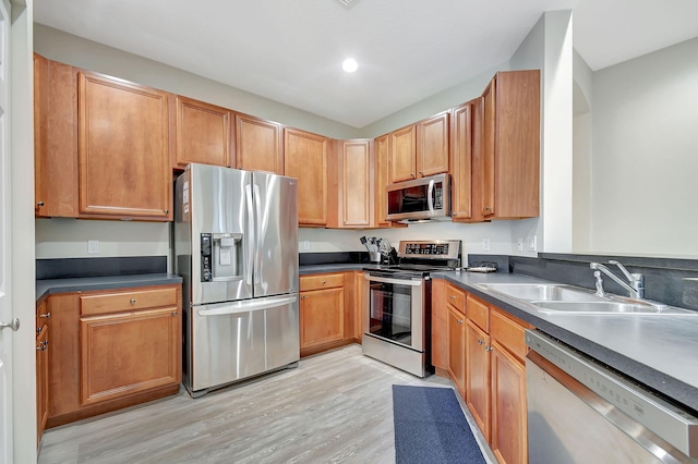 kitchen with appliances with stainless steel finishes, sink, and light hardwood / wood-style flooring