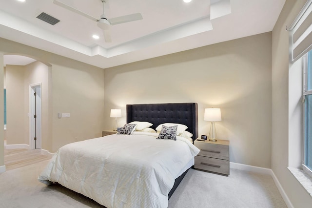 carpeted bedroom featuring ceiling fan and a raised ceiling