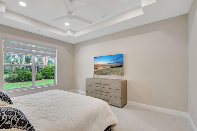 carpeted bedroom featuring a tray ceiling and ceiling fan