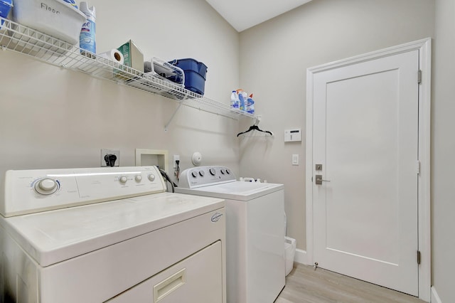 clothes washing area featuring separate washer and dryer and light wood-type flooring