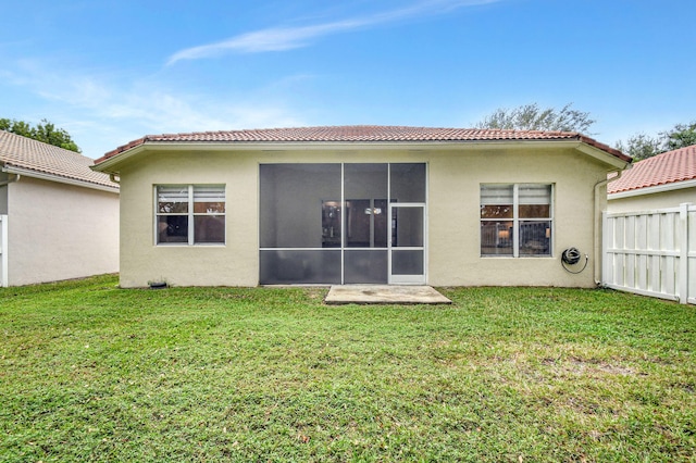 rear view of house featuring a sunroom and a yard