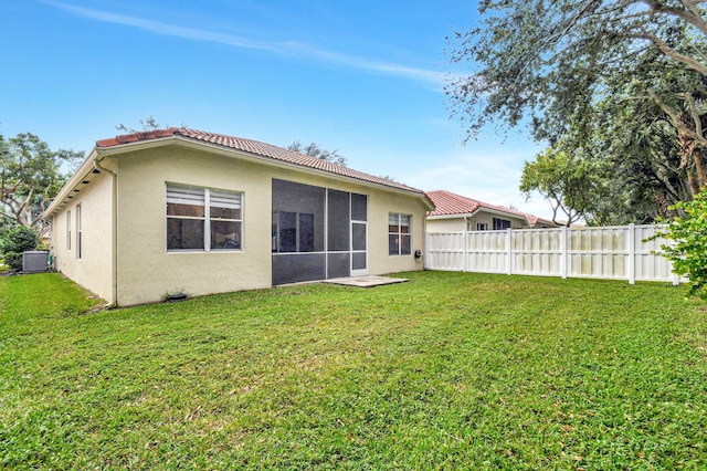 rear view of property with a sunroom, a yard, and cooling unit