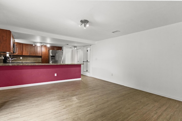 kitchen with dark wood-type flooring, a breakfast bar, stainless steel refrigerator with ice dispenser, decorative backsplash, and kitchen peninsula