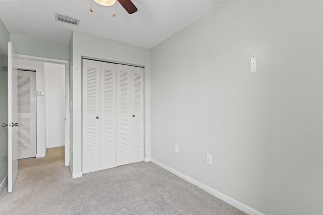 unfurnished bedroom featuring light colored carpet, ceiling fan, and a closet