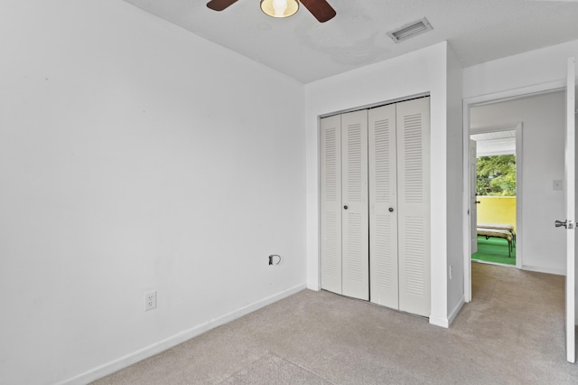 unfurnished bedroom featuring ceiling fan, a closet, and light carpet