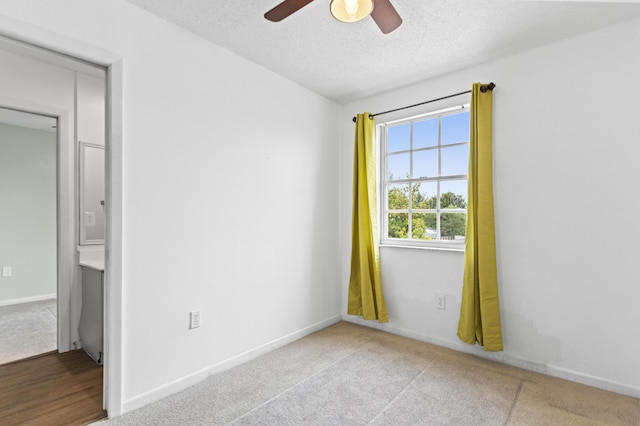 carpeted spare room with ceiling fan and a textured ceiling