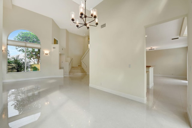 interior space with a high ceiling, light tile patterned floors, and a notable chandelier