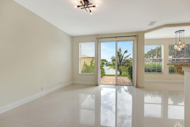 entryway featuring light tile patterned flooring, a textured ceiling, and a notable chandelier