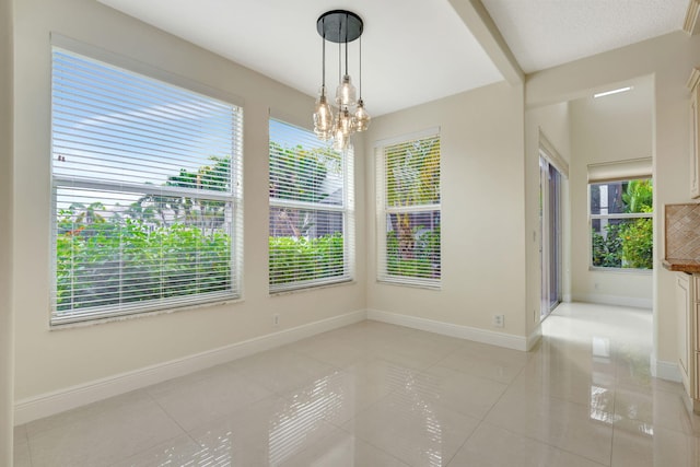 unfurnished dining area featuring plenty of natural light, light tile patterned floors, and a chandelier