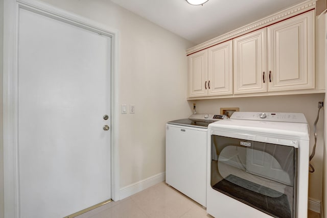 washroom featuring washing machine and dryer, cabinets, and light tile patterned floors