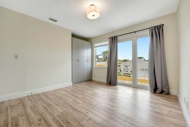 spare room featuring a textured ceiling and light hardwood / wood-style flooring