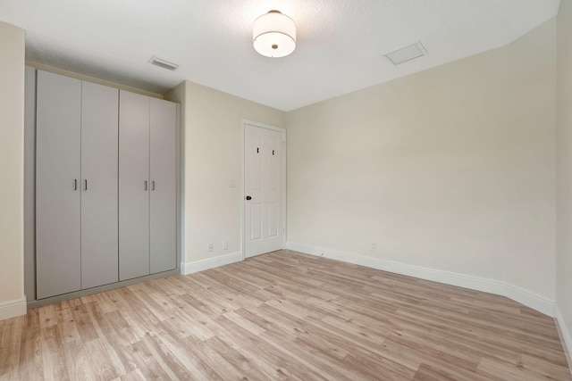 unfurnished bedroom with a closet, light wood-type flooring, and a textured ceiling