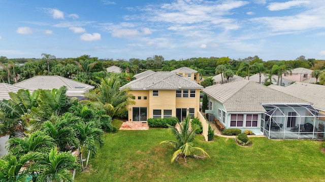 rear view of house with a lanai and a lawn