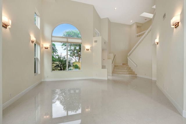 unfurnished living room with a high ceiling and light tile patterned floors