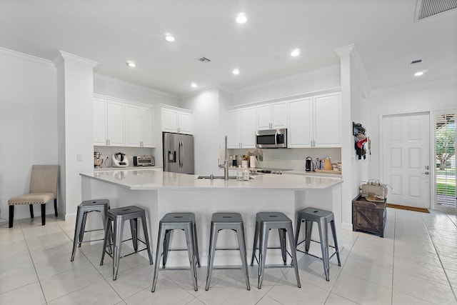 kitchen featuring white cabinets, a kitchen bar, a spacious island, and appliances with stainless steel finishes