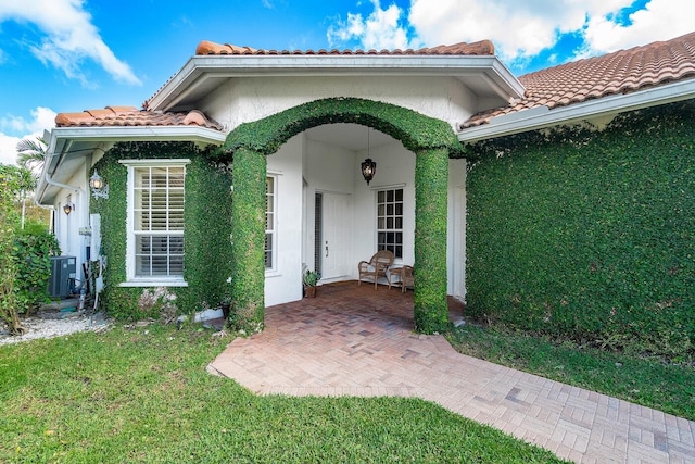 property entrance with central AC and a yard