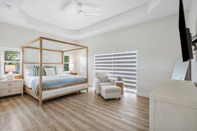 bedroom featuring multiple windows, a raised ceiling, and ceiling fan